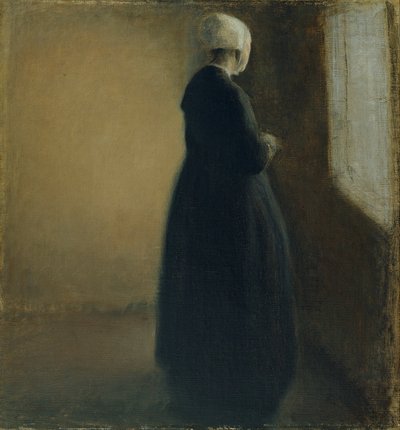 An old woman standing by a window by Vilhelm Hammershøi